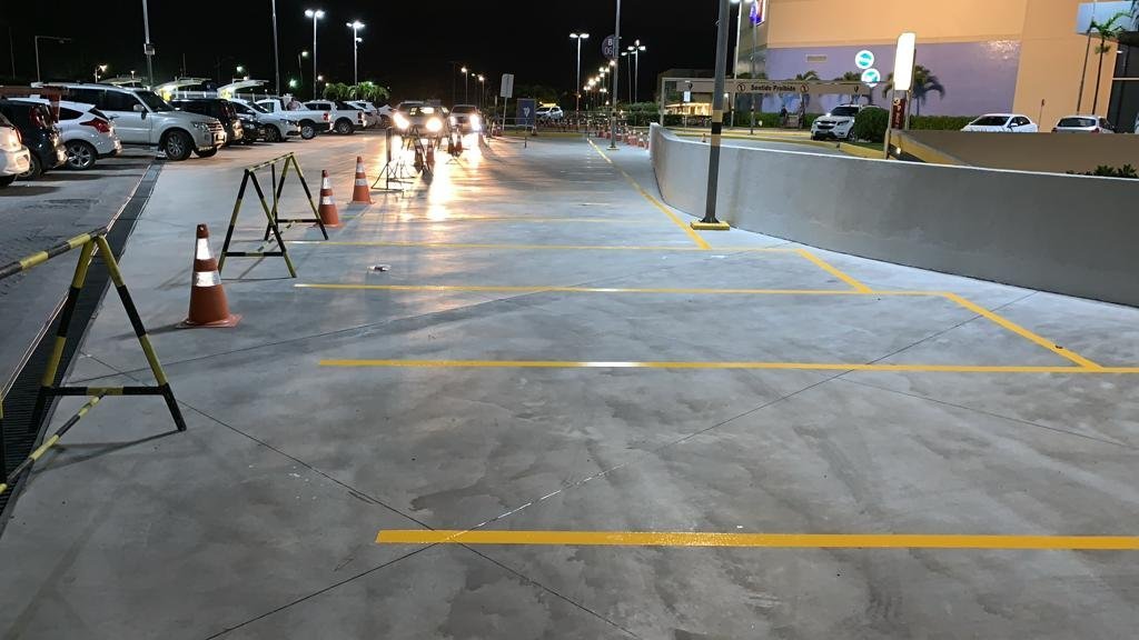 Demarcação de piso em estacionamento externo com faixas amarelas e área de circulação