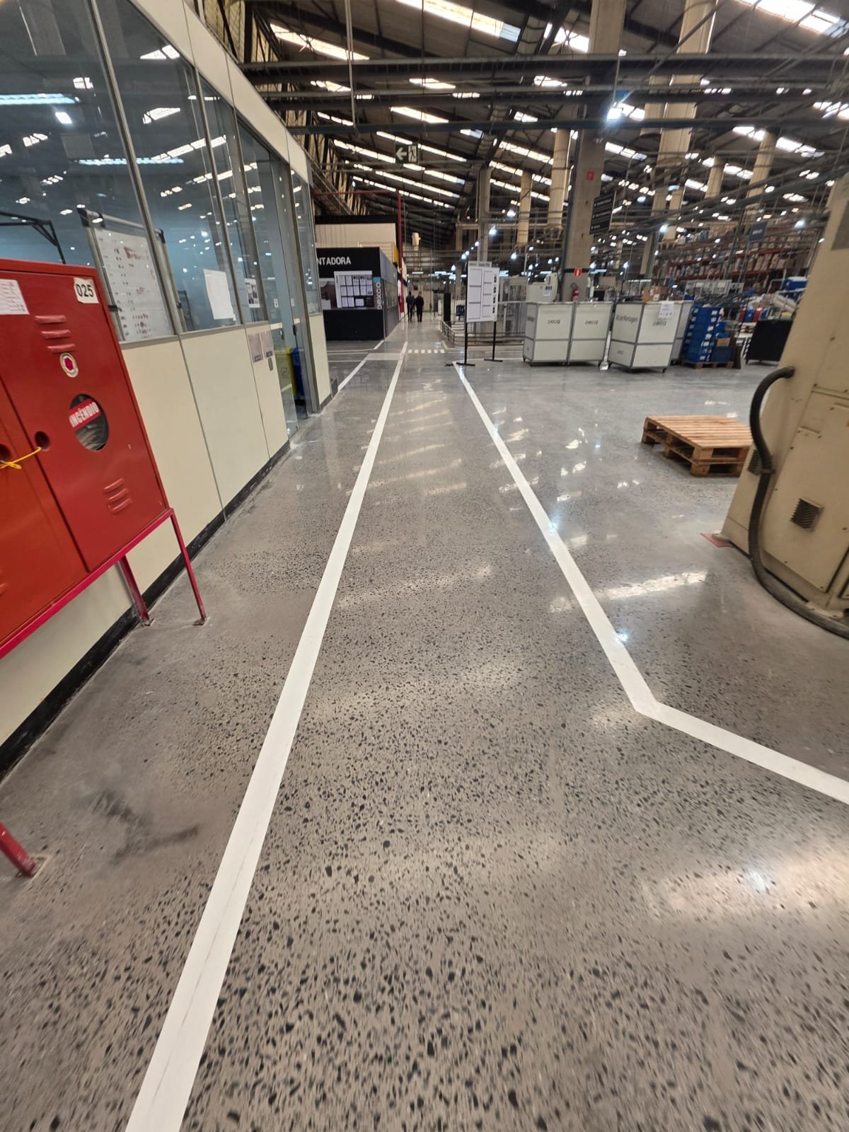 Demarcação de piso em estacionamento externo com faixas amarelas e área de circulação