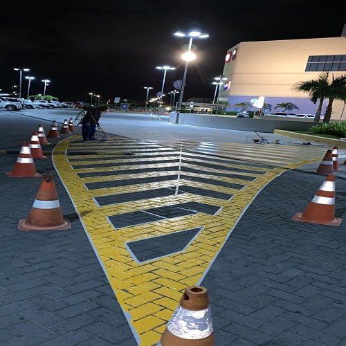 Demarcação de piso em estacionamento externo com faixas amarelas e área de circulação
