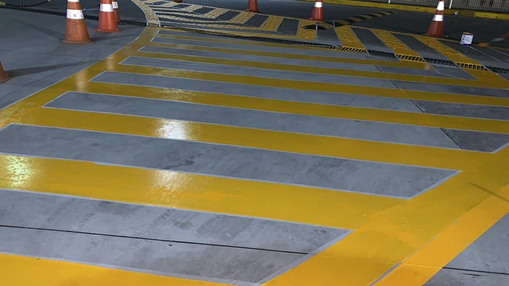 Demarcação de piso em estacionamento externo com faixas amarelas e área de circulação