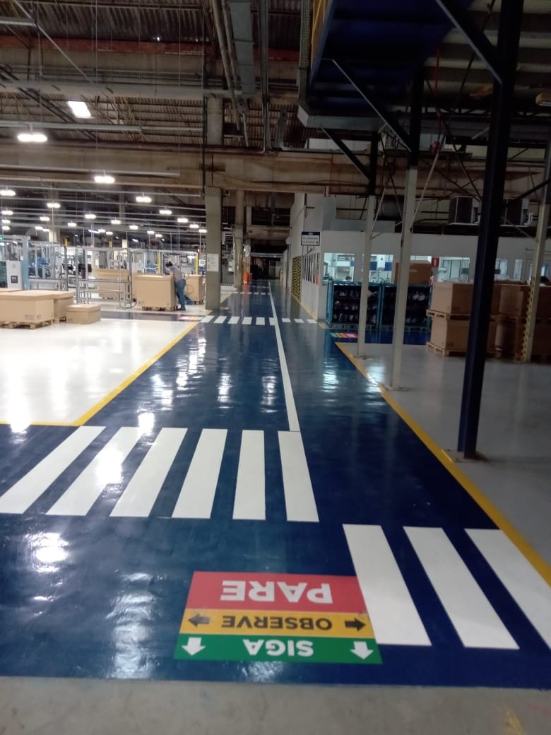 Piso industrial brilhante com faixas amarelas de demarcação em centro de distribuição
