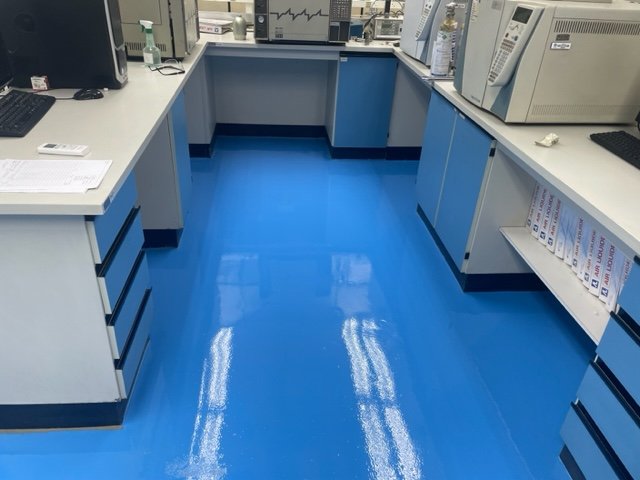 Piso epóxi azul aplicado em laboratório com acabamento brilhante e superfície lisa
